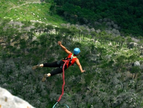 Mujer saltando en bungee jumping en medio de la naturaleza.