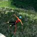 Mujer saltando en bungee jumping en medio de la naturaleza.