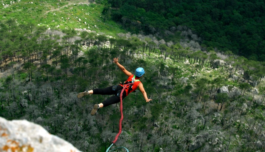 Mujer saltando en bungee jumping en medio de la naturaleza.