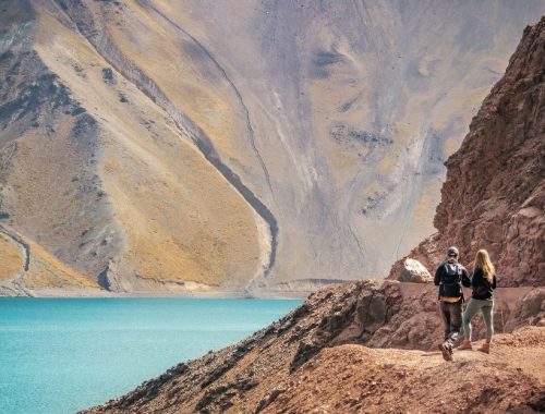 Pareja observando un mar de aguas cristalinas y montañas en el Cajón del Maipo.