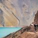 Pareja observando un mar de aguas cristalinas y montañas en el Cajón del Maipo.