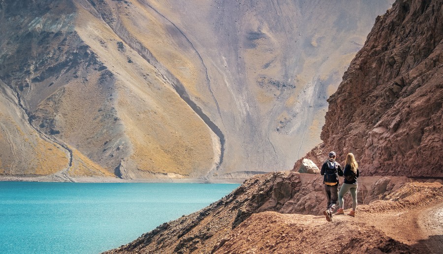 Pareja observando un mar de aguas cristalinas y montañas en el Cajón del Maipo.