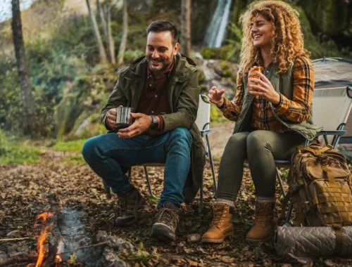 Pareja feliz acampando en Cajón del Maipo alrededor de una fogata