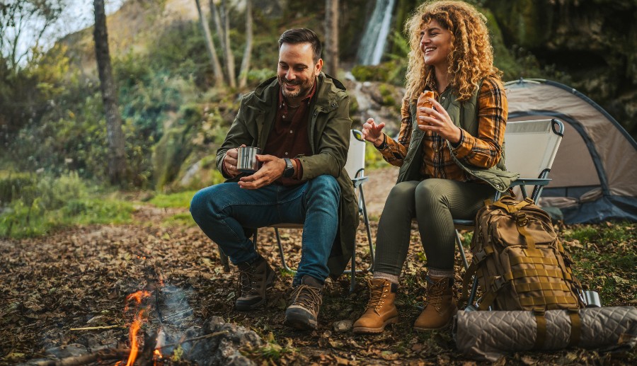Pareja feliz acampando en Cajón del Maipo alrededor de una fogata