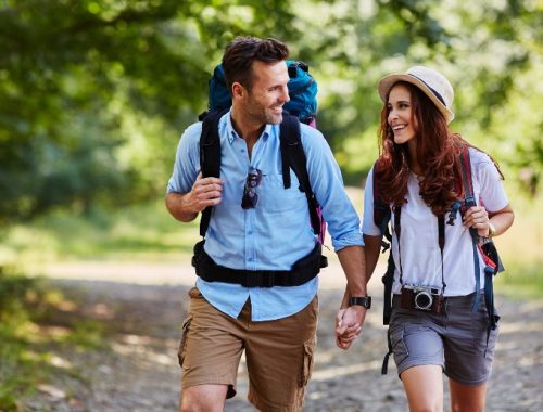 Pareja haciendo senderismo con mochila y cámara fotográfica