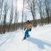 Mujer esquiando en la nieve con varios árboles secos detrás