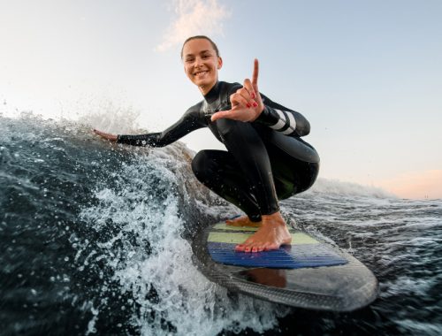 Mujer surfeando y haciendo una señal para posar en una foto