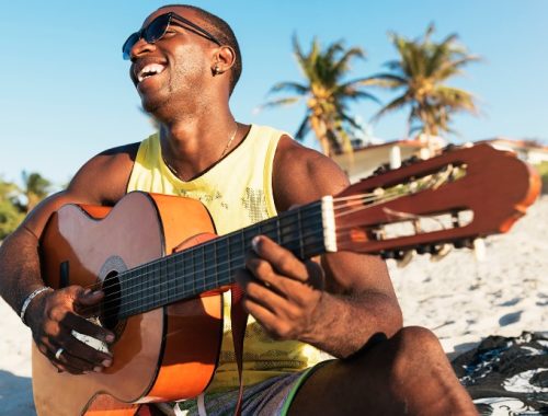 Hombre negro tocando la guitarra en la playa