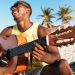 Hombre negro tocando la guitarra en la playa