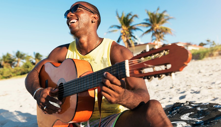 Hombre negro tocando la guitarra en la playa