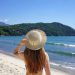 Mujer de espaldas observando la playa de Ilhabela con un sombrero en la cabeza