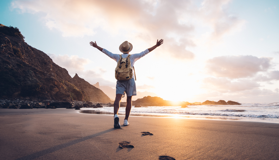 Hombre con los brazos abiertos al atardecer en una playa