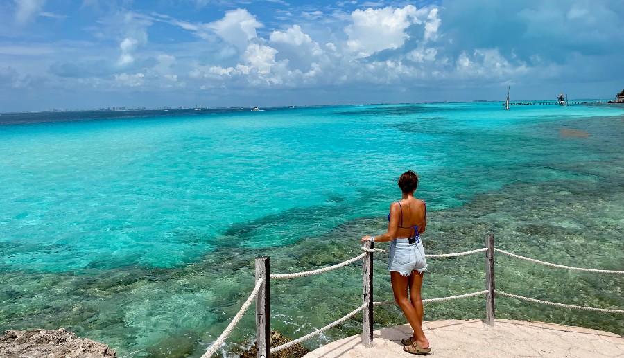 Mujer observando el mar con aguas cristalinas en un día soleado