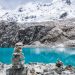 Imagen de paisaje con montañas y un lago azul cristalino con algunas rocas apiladas
