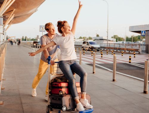 Pareja divirtiéndose mientras transporta las maletas en el aeropuerto