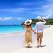 Pareja caminando por la playa de la mano con vista a aguas cristalinas