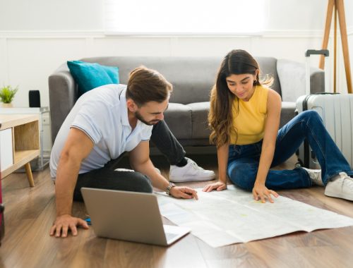 Pareja planificando un viaje de Puerto Natales a Punta Arenas con un mapa en la sala de su casa