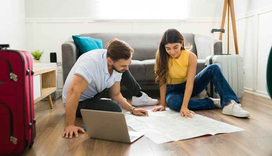Pareja planificando un viaje de Puerto Natales a Punta Arenas con un mapa en la sala de su casa