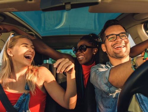 Grupo de amigos felices viajando dentro del coche