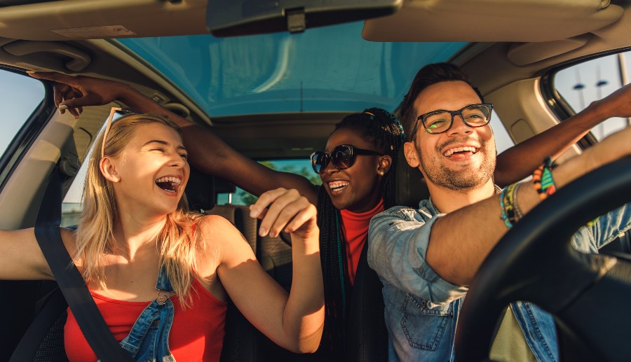 Grupo de amigos felices viajando dentro del coche