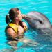 Mujer dentro de las aguas de Punta Cana dando un beso a un delfín
