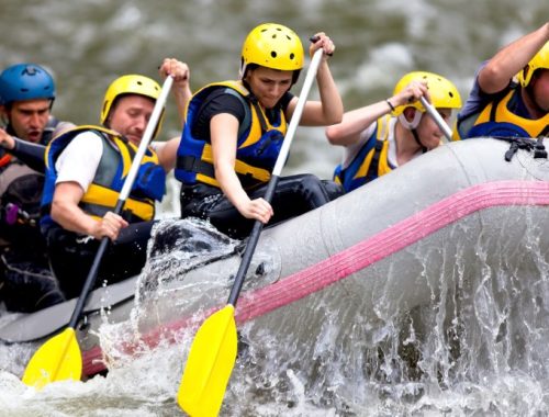 Grupo de personas blancas dentro de una canoa, remando en un río.