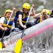 Grupo de personas blancas dentro de una canoa, remando en un río.