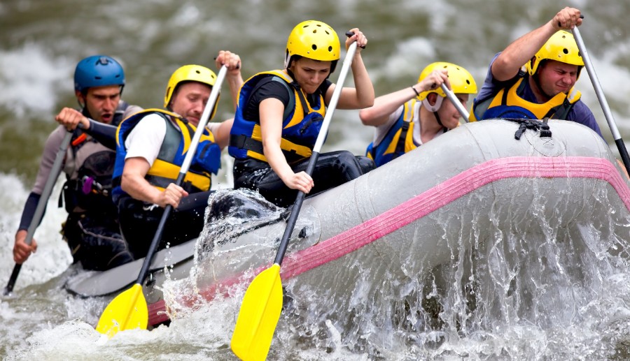 Grupo de personas blancas dentro de una canoa, remando en un río.
