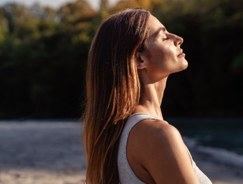 Mujer de cabello largo y ojos cerrados tomando el sol en un retiro espiritual