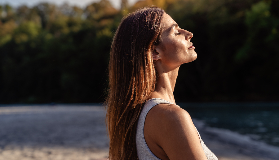 Mujer de cabello largo y ojos cerrados tomando el sol en un retiro espiritual