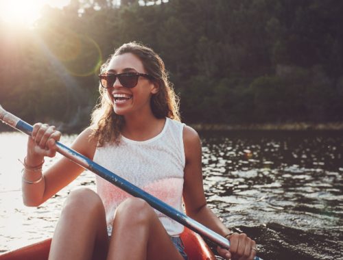Mujer sonriente remando en canoa en el río Itata.