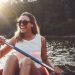 Mujer sonriente remando en canoa en el río Itata.