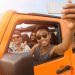 Grupo de amigos dentro de un mini auto naranja posando para una selfie