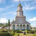 Imagen de iglesia rodeada por casas y céspedes