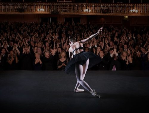 Bailarina con ropa negra finalizando su presentación y siendo ovacionada por el público