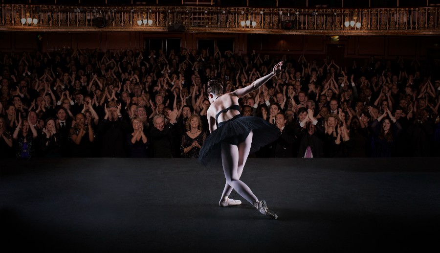 Bailarina con ropa negra finalizando su presentación y siendo ovacionada por el público