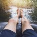 Hombre con los pies fuera del flotador practicando tubing en un río
