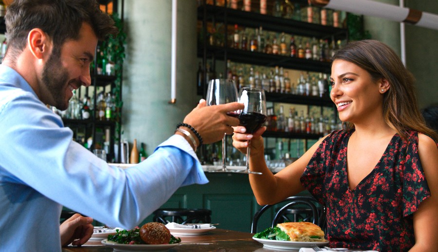 Casal brindando com taça de vinho em restaurante