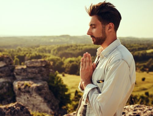 Hombre con las manos juntas en señal de oración y los ojos cerrados