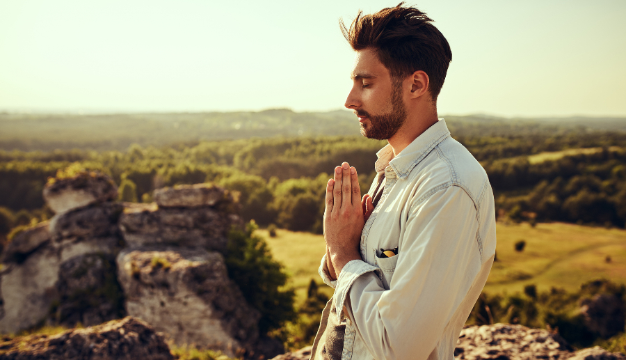 Hombre con las manos juntas en señal de oración y los ojos cerrados
